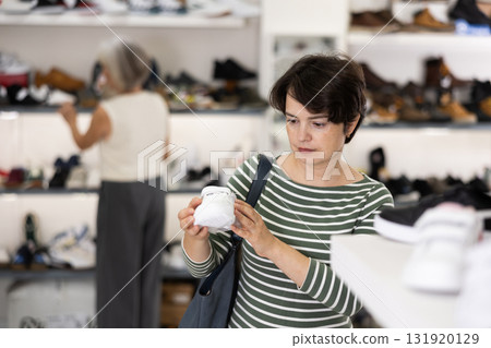 Woman takes samples from showcase and examines snickers 131920129