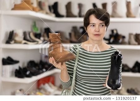 Woman takes samples from showcase and examines shoes 131920137