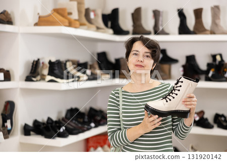 Woman takes samples from showcase and examines shoes Woman takes samples from showcase and examines shoes 131920142