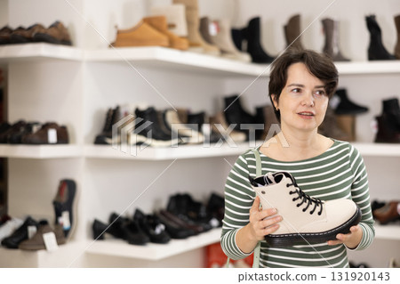 Adult woman chooses boots in shoe store 131920143