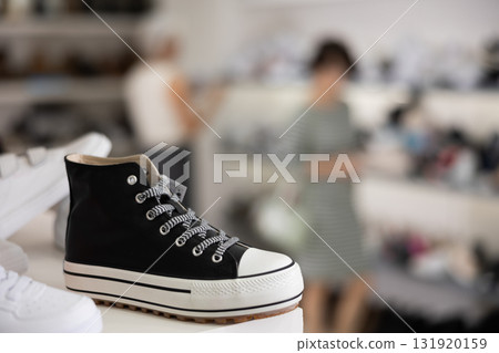 There are gym shoes and sports shoes on shelf in store 131920159