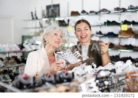 Elderly woman and young woman choosing sandals in shoe store Elderly woman and young woman choosing sandals in shoe store 131920172