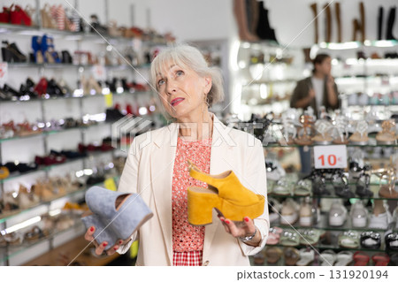 Elderly woman chooses mules in shoe store Elderly woman chooses mules in shoe store 131920194