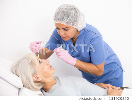 Old woman having mesotherapy procedure on her face 131920220