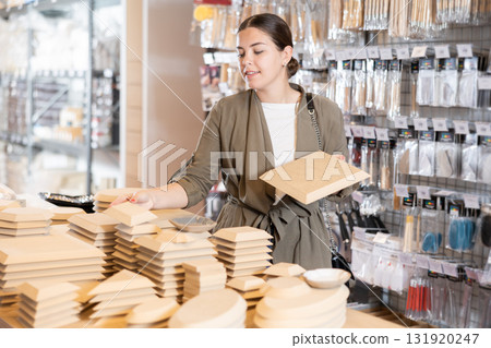 Woman chooses various wooden molds for future clay molding in her workshop 131920247