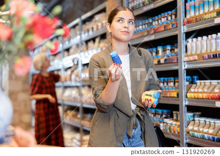 Female customer chooses multi-colored pigments for her future earthenware or ceramic tableware in specialty store 131920269
