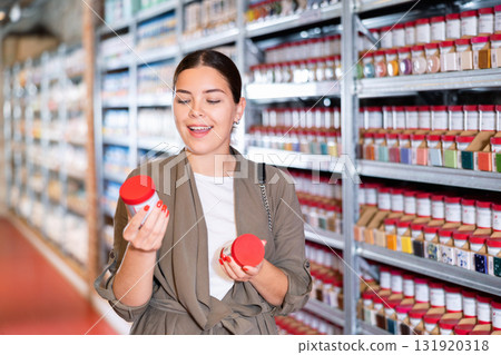 Female shopper choosing pottery glaze jars in pottery specialty store 131920318