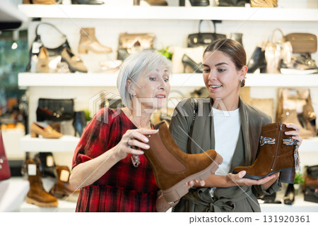 Young girl with elderly mother choosing demi-season footwear in shoe boutique 131920361