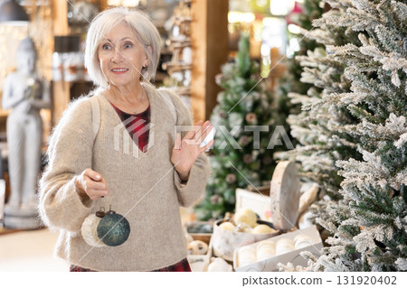 Mature woman purchasing christmas toys and decorations at christmas fair shop 131920402