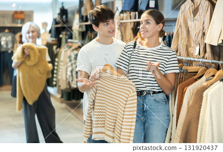 Young couple choosing convenient jumper in clothing store 131920437