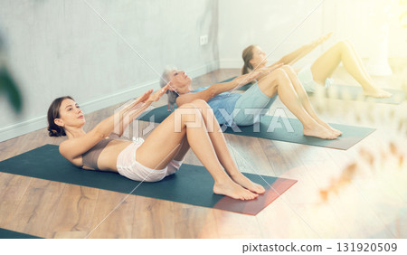 Young woman doing abdominal crunches during group yoga class 131920509
