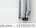 Gray metal fan pipe on buiding wall outside the buidling 131920535