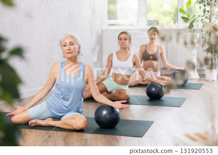 Elderly woman doing pilates with soft ball in group 131920553