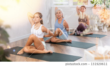 Teenage girl doing Matsyendrasana with hands clasped in lock behind back 131920611