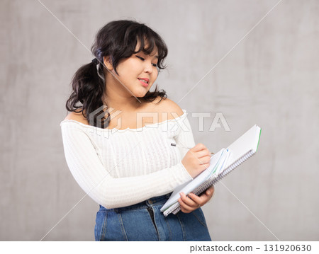 Smiling young girl making notes in studio 131920630