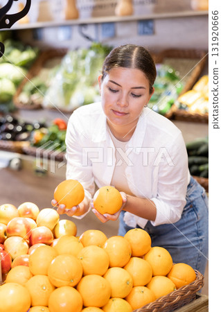 Young girl selecting ripe oranges while shopping in supermarket 131920666