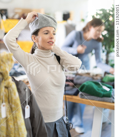 Female shopper chooses a hat in clothing store 131920851