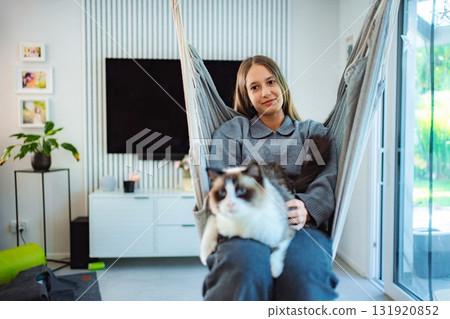 Teenager relaxing in hammock with ragdoll cat at home Teenager relaxing in hammock with ragdoll cat at home 131920852