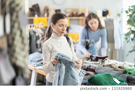Attentive middle-aged woman choosing jean pantaloons in clothing store Attentive middle-aged woman choosing jean pantaloons in clothing store 131920860