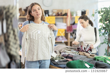 Young woman choosing sweater in clothing store Young woman choosing sweater in clothing store 131920867