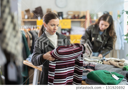 Attentive middle-aged woman choosing sweater in clothing store 131920892