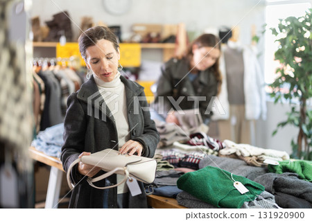 Selective middle-aged woman choosing handbag in clothing store Selective middle-aged woman choosing handbag in clothing store 131920900