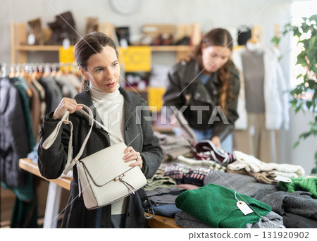 Selective middle-aged woman choosing handbag in clothing store Selective middle-aged woman choosing handbag in clothing store 131920902