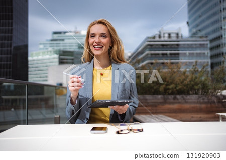 Young businesswoman smiling, working outdoors with tablet in city Young businesswoman smiling, working outdoors with tablet in city 131920903