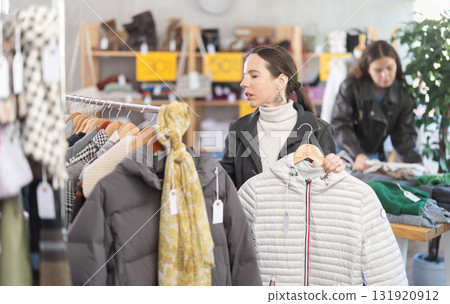 Middle-aged woman choosing down jacket in clothing store Middle-aged woman choosing down jacket in clothing store 131920912