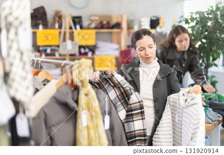 Adult woman chooses outerwear in store Adult woman chooses outerwear in store 131920914