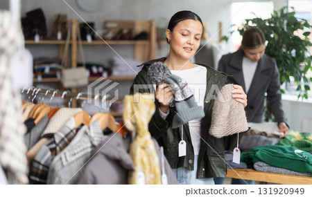 Focused asian young woman choose hat for autumn-winter season in clothing store Focused asian young woman choose hat for autumn-winter season in clothing store 131920949