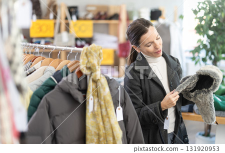 Adult woman choosing fur hat in clothing store 131920953