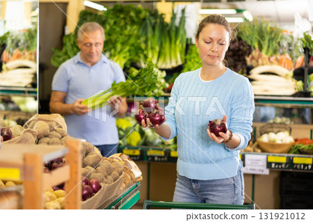 Middle-aged woman purchaser buying red onions in grocery store Middle-aged woman purchaser buying red onions in grocery store 131921012