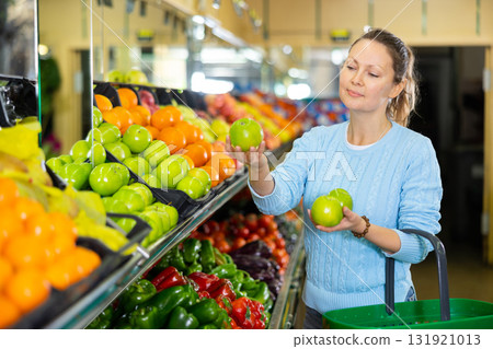 Middle-aged woman purchaser buying fresh apples in grocery store Middle-aged woman purchaser buying fresh apples in grocery store 131921013