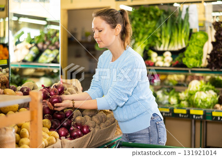 woman buy large onion in supermarket 131921014