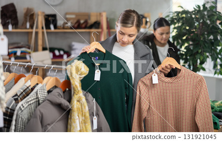 Adult woman chooses warm dress in clothing store 131921045