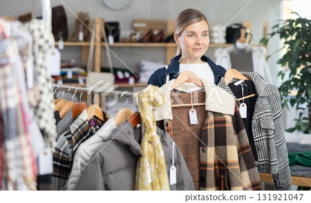 Adult woman chooses plaid jacket in clothing store Adult woman chooses plaid jacket in clothing store 131921047