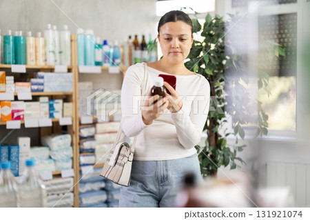 Asian woman scans medicinal syrup in pharmacy 131921074
