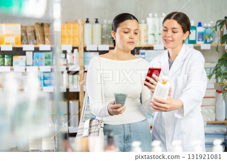 Asian female client choosing cream or skin care product in pharmacy and scan QR code on label, young woman pharmacist consulting and offering variety of goods to customer Asian female client choosing cream or skin care product in pharmacy and scan QR code on label, young woman pharmacist consulting and offering variety of goods to customer 131921081
