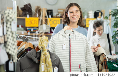 Happy girl chooses fashionable down jacket in clothing store Happy girl chooses fashionable down jacket in clothing store 131921082