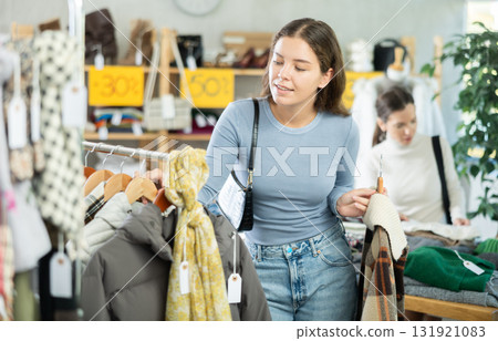 Young woman chooses different winter clothes in clothing store Young woman chooses different winter clothes in clothing store 131921083