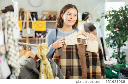 Pregnant woman chooses checkered jacket searches for fashionable clothes in clothing boutique Pregnant woman chooses checkered jacket searches for fashionable clothes in clothing boutique 131921086