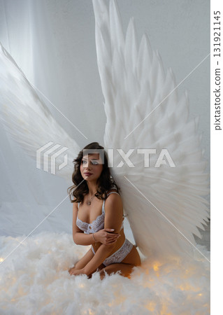 Beauty woman poses topless with angel wings in a dreamy studio setting Beauty woman poses topless with angel wings in a dreamy studio setting 131921145