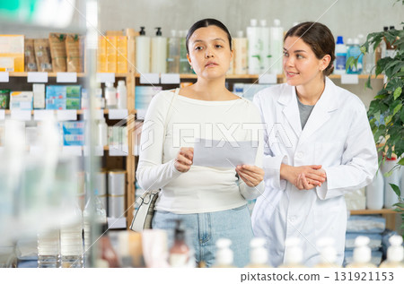 Young woman with prescription looking for medicines in pharmacy 131921153
