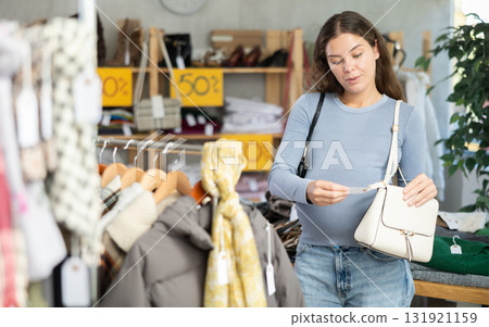 Pregnant woman choosing handbag in clothing store Pregnant woman choosing handbag in clothing store 131921159