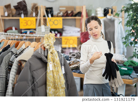 Woman carefully selects warm winter gloves in clothing store Woman carefully selects warm winter gloves in clothing store 131921179