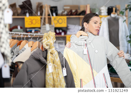 Middle-aged woman choosing down jacket in clothing store 131921249