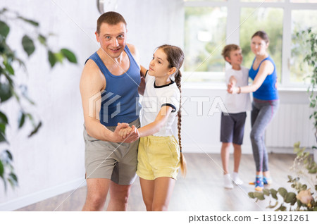 Happy father and daughter practicing dance in pairs together with other family members 131921261