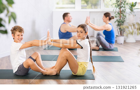 Brother and sister pair doing yoga in gym 131921265