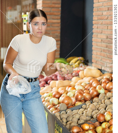Young shopper dissatisfied with the quality of potatoes in supermarket Young shopper dissatisfied with the quality of potatoes in supermarket 131921301